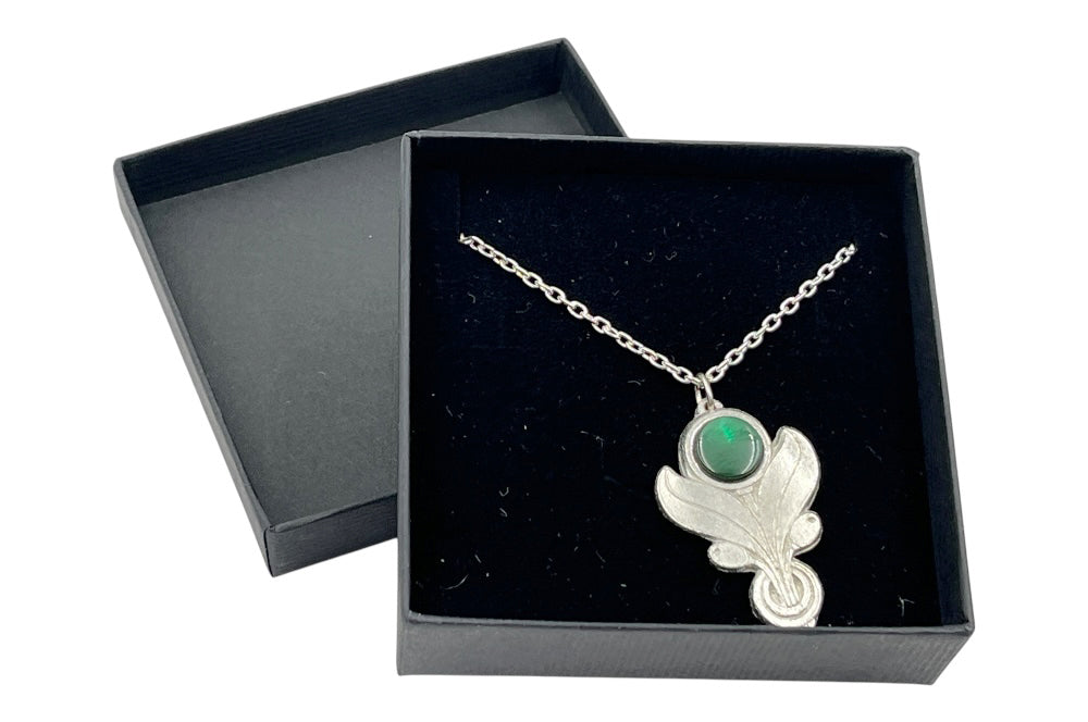 Feine silberne Halskette mit einem Anhänger aus Zinn. Der Anhänger ist floral geformt und trägt oben einen glatten, runden, dunkelgrünen Stein. in einer schänen schwarzen Geschenksschachtel