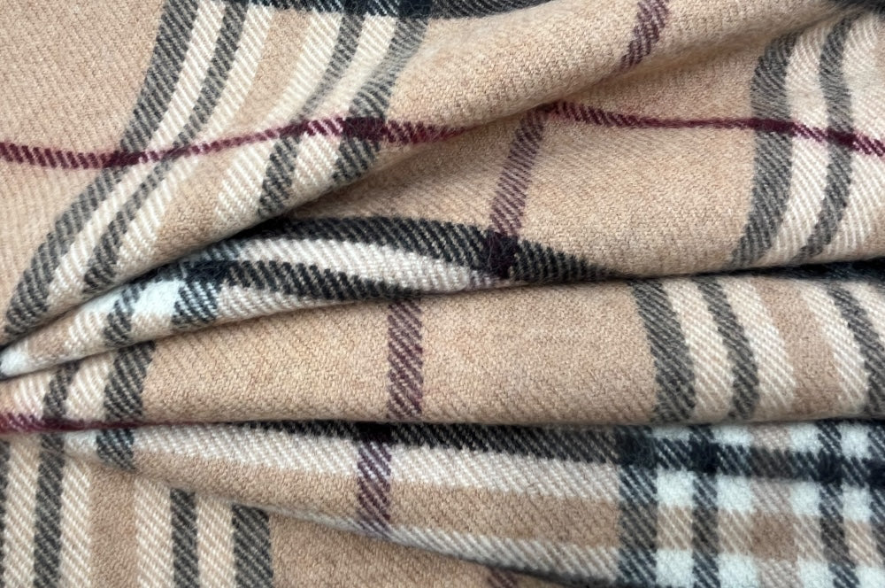 Herrenschal aus 100% Schurwolle mit klassischem Karodesign in Beige mit schwarzen und weißen Akzenten. gefaltet