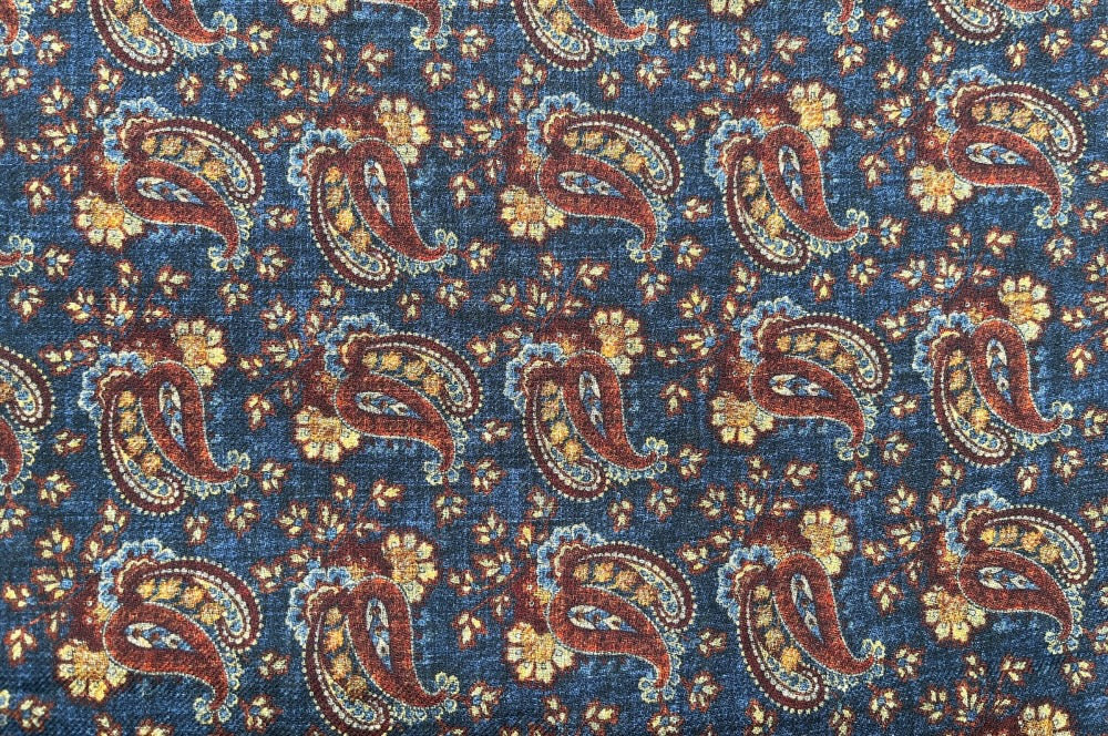 Doppelseitiger Herrenschal aus feinster Wolle mit Paisley-Muster in Dunkelblau, Braun und Orange und einer Seite mit quadratischem Muster in Dunkelblau. detailansicht design