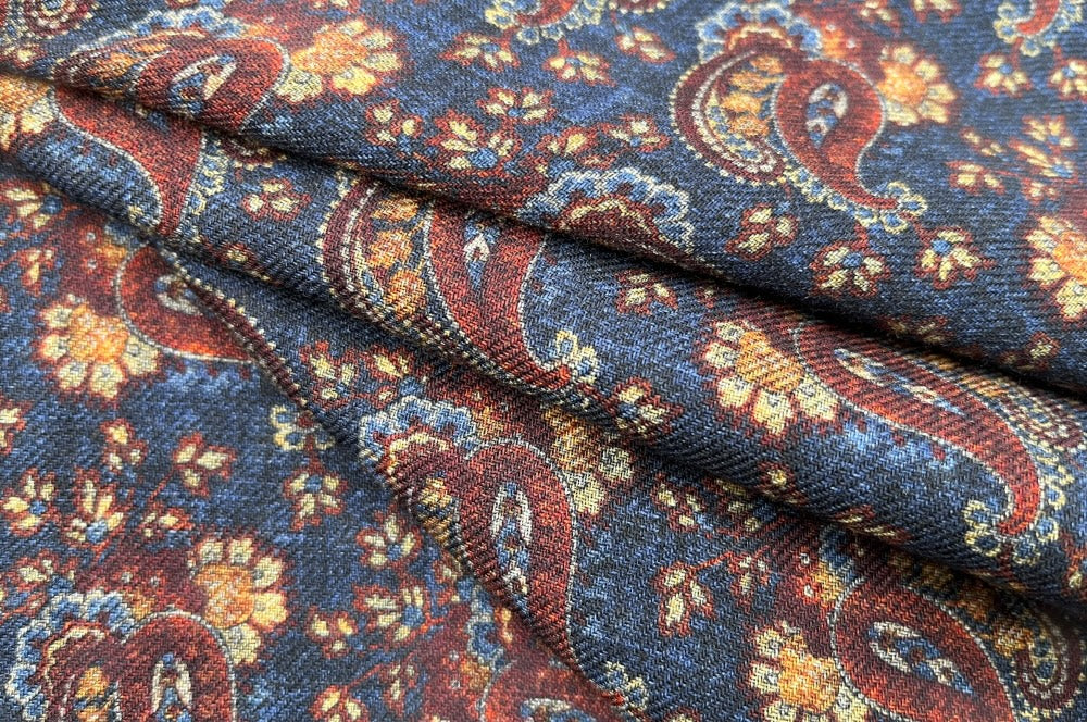 Doppelseitiger Herrenschal aus feinster Wolle mit Paisley-Muster in Dunkelblau, Braun und Orange und einer Seite mit quadratischem Muster in Dunkelblau. in Falten gelegt