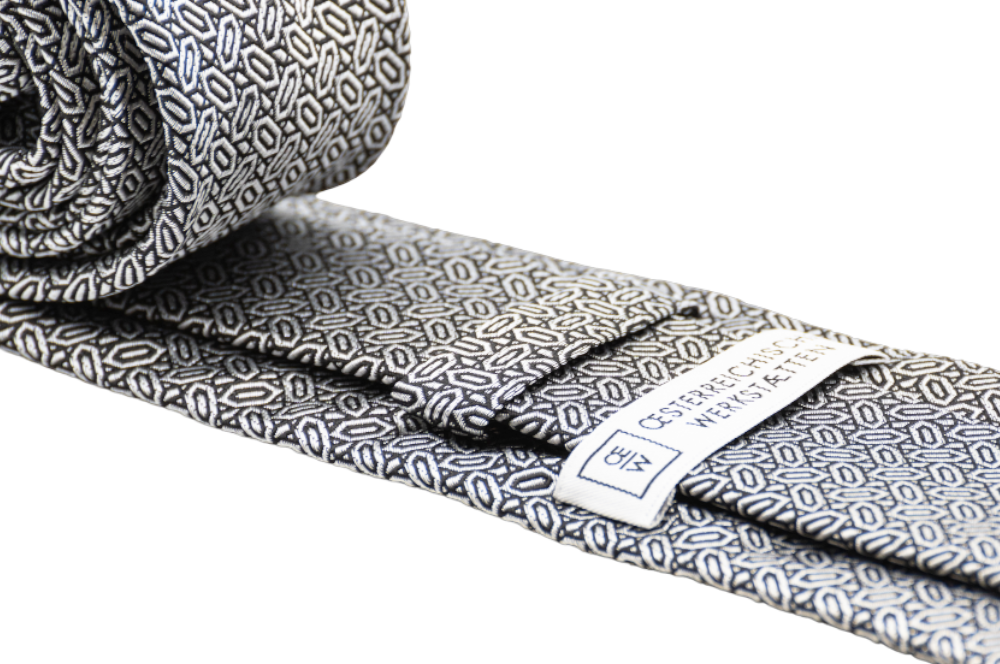 seidenkrawatte in silber mit diamantmuster, zusammengerollt, detailansicht logo