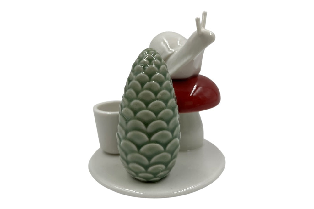 Weißer Herzenhalter mit einer kleinen Schnecke die auf einem roten Pilz sitz, daneben ein grüner ZapfenZapfen, Ansicht von der Seite