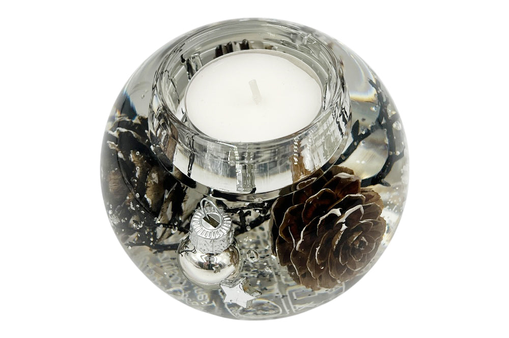 Teelichthalter aus Glas, mit weißen Christbaumkugelen, Kieferzapfen und weißen Schneesternen gefüllt. Ansicht seitlich oben